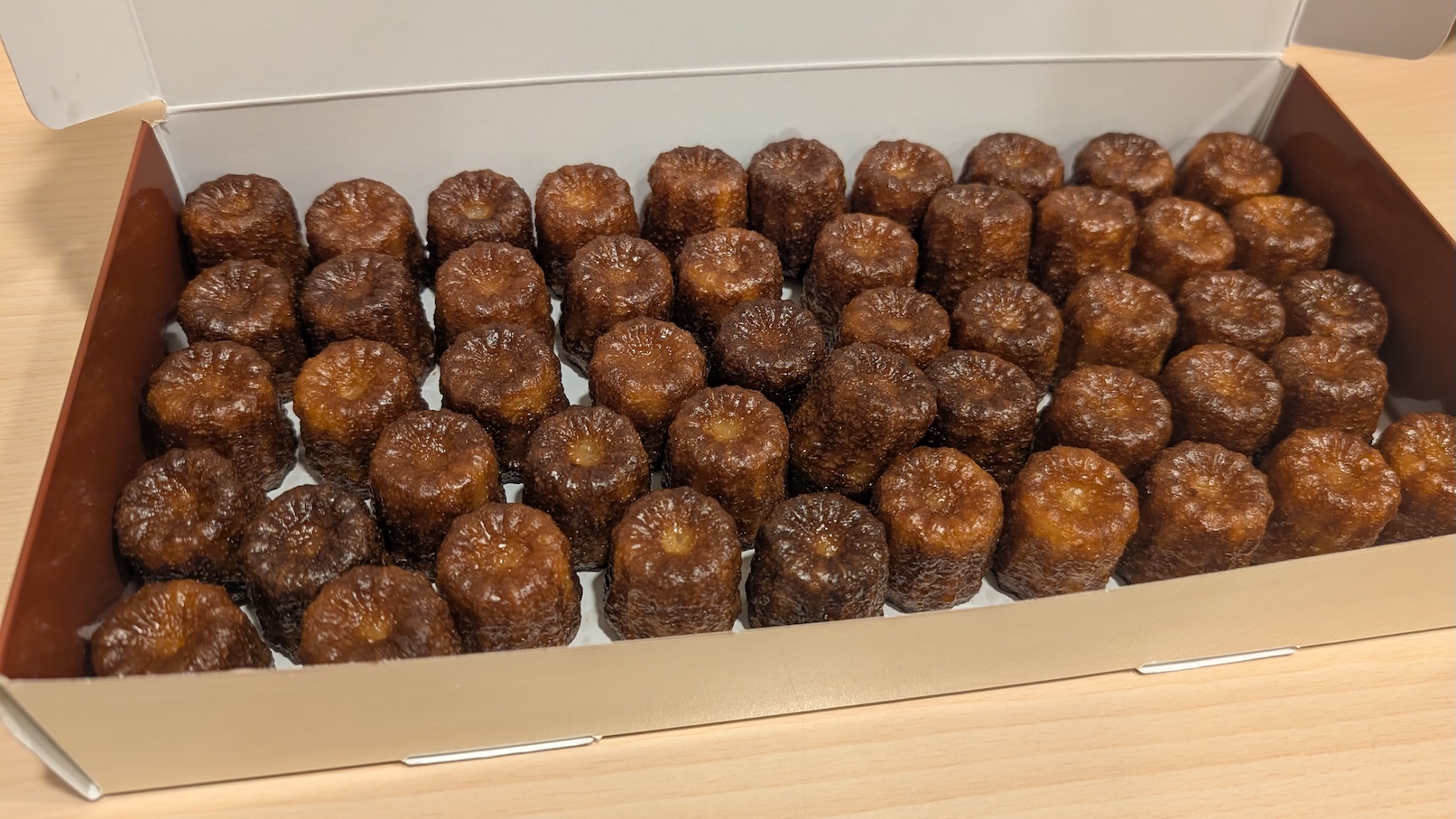 Photo de la boîte de canelés ouverte, remplie de petits canelés de Bordeaux